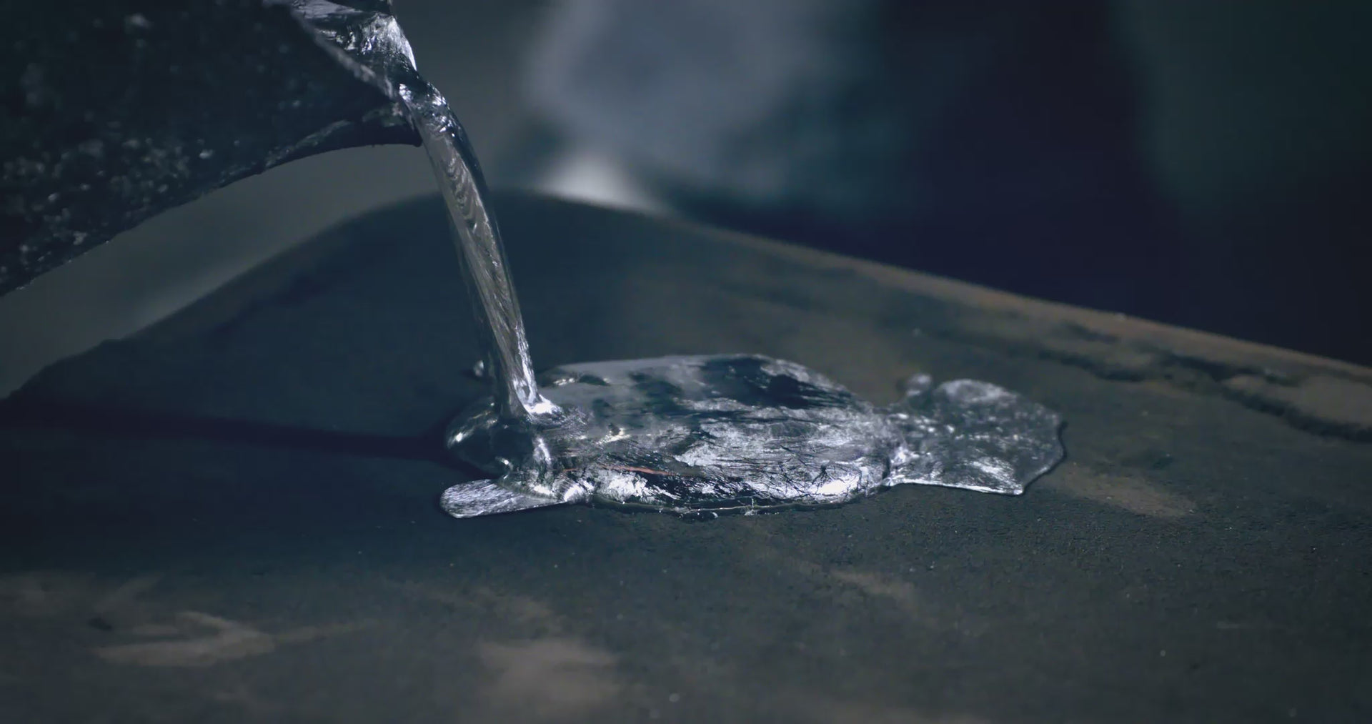 Close-up of silver pewter being poured onto a dark surface